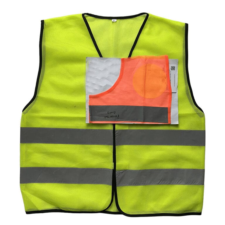 High visibility fluorescent yellow mesh safety vest in daylight with a reflective tape quality sample pinned to the front