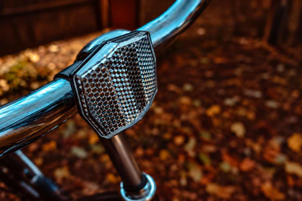 Colourless front bicycle reflector clamped to a chrome handlebar