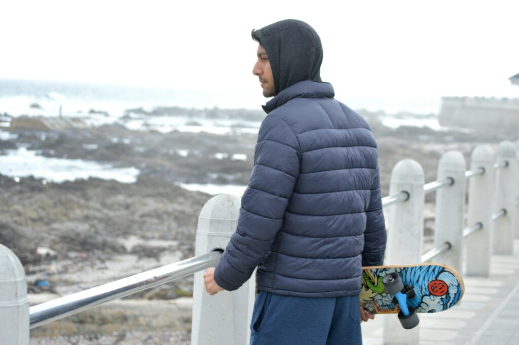 Back view of a navy hooded puffer jacket showing sewn-through quilted baffles