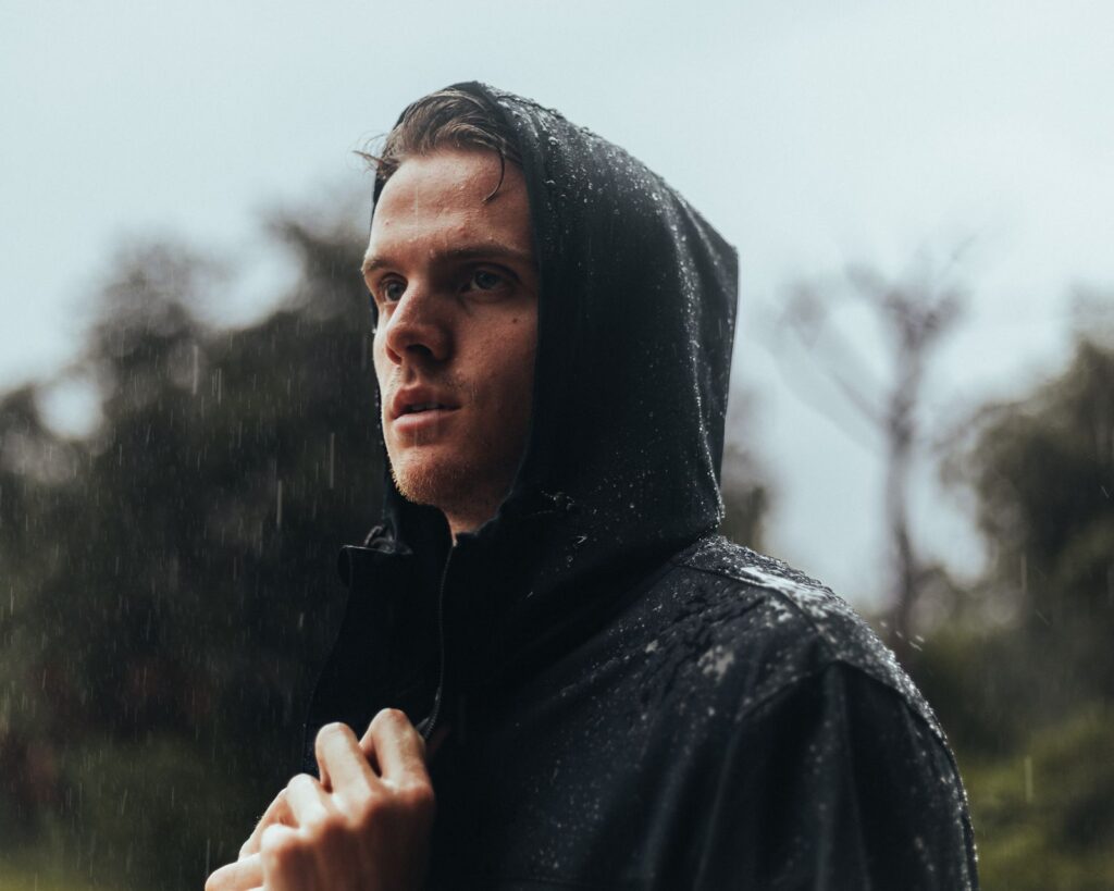 Rain beading on the hood and shoulders of a dark waterproof jacket