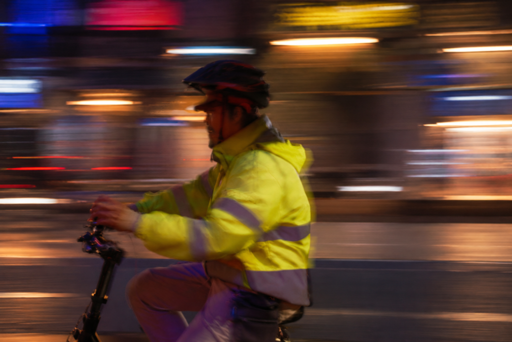 Cyclist in a fluorescent yellow jacket with reflective bands riding at night