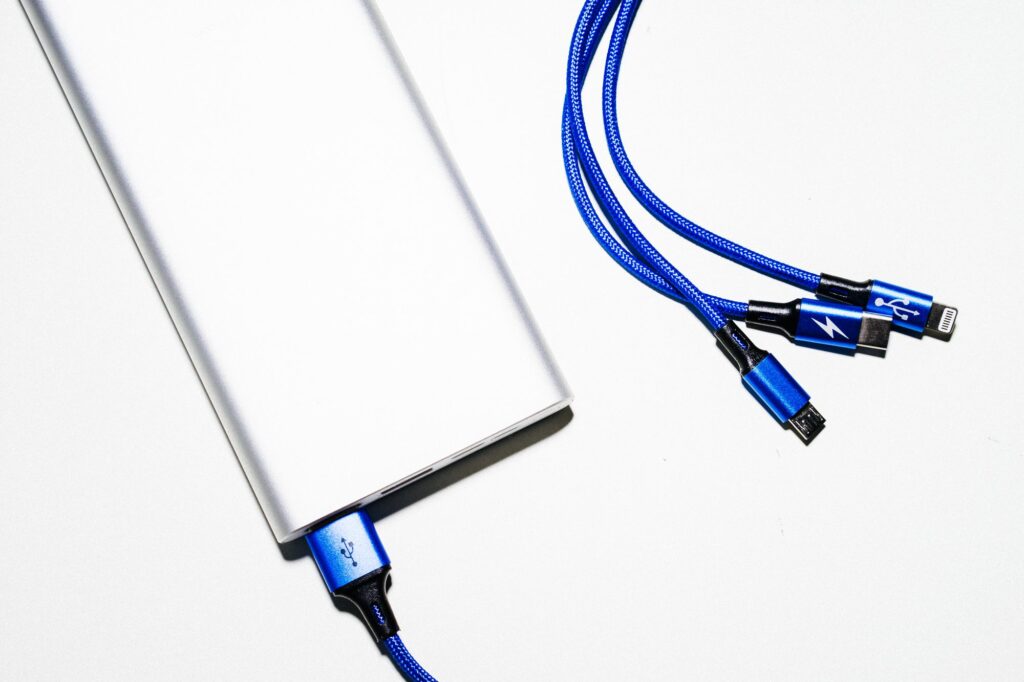 Silver power bank with blue braided USB charging cables on a white surface